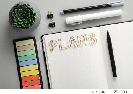 Open diary for plans with with black and white school and office stationery on gray background. Flatly. Concept of planning and resolution. 112935553