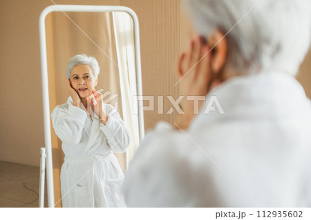 Love yourself. Beautiful old woman enjoying mirror reflection. Senior older lady spending morning in bathroom looking at mirror confident happy. Woman doing daily morning beauty routine. Self love Love yourself. Beautiful old woman enjoying mirror reflection. Senior older lady spending morning in bathroom looking at mirror confident happy. Woman doing daily morning beauty routine. Self love 112935602