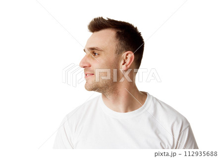 Young man with short hair and stubble turned his head to side showing off his chin and cheekbones against white studio background. Young man with short hair and stubble turned his head to side showing off his chin and cheekbones against white studio background. 112935688