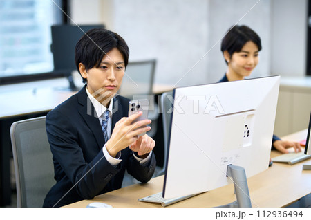 オフィスでスマホを操作する若いビジネスマン 112936494