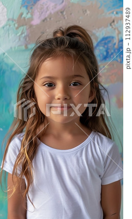 Hispanic child girl 4-6 years old in a white T-shirt without a pattern against the background of a colored wall 112937489
