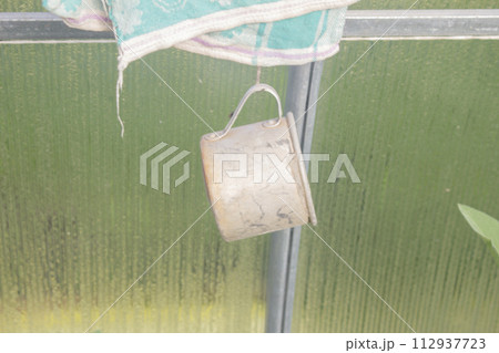 Old rusty tin mug hanging on a peg Old rusty tin mug hanging on a peg 112937723