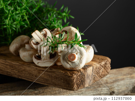 White champignons with rosemary on a wooden board. White champignons with rosemary on a wooden board. 112937860
