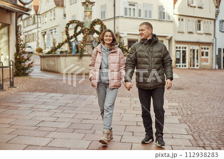 Loving couple of tourists walking around old town. Couple of lovers leisurely stroll in the cool autumn morning on the streets of a BIETIGHEIM-BISSINGEN (Germany). The guy holds his wife. Vacation 112938283