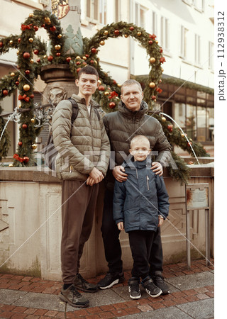 Joyful Family Portrait: Father and Two Sons by Festive Vintage Fountain. Joyful Family Portrait: Father and Two Sons by Festive Vintage Fountain. 112938312