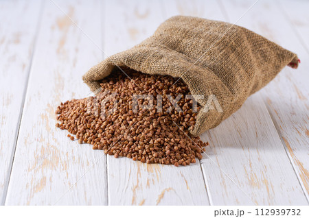 Raw buckwheat in sack on a light table, selective focus. 112939732