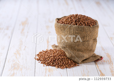 Raw buckwheat in sack on a light table, selective focus. Raw buckwheat in sack on a light table, selective focus. 112939733