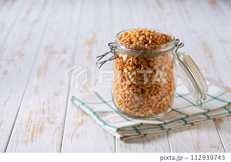 Raw dried peas in glass storage jar on a white wooden table. 112939743