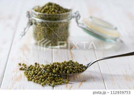 metal spoon with mung beans on a light table, selective focus. metal spoon with mung beans on a light table, selective focus. 112939753