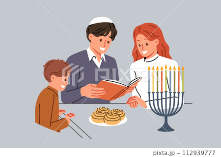 Jewish family celebrates day hanukkah and reads holy book together, standing near table and minors 112939777
