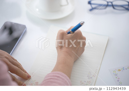手紙を書くミドル女性の手元 112943439