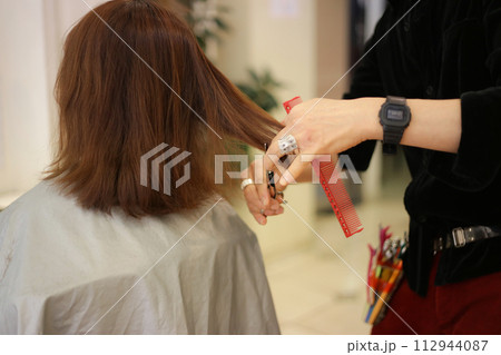 女性の髪を切る男性美容師 112944087