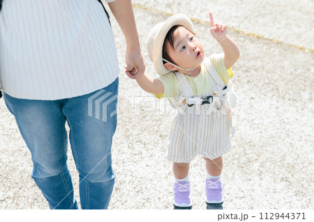 ママと手を繋ぎ歩く乳幼児　指を差す　興味　好奇心　疑問　散歩　お出かけ　遊園地 112944371
