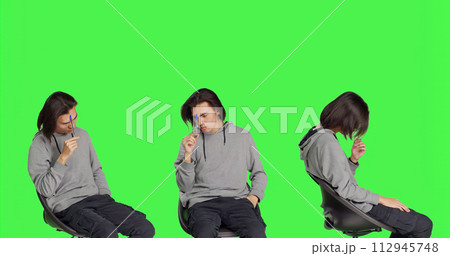 Male model thinking about solution over greenscreen backdrop, feeling uncertain about new dilemma. Asian man sitting on chair and acting confused, pensive thoughtful person. 112945748