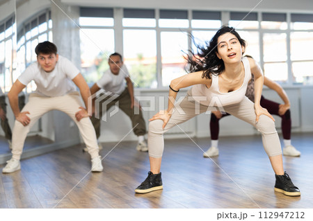 Young girl with waving hair energizing group during dance class 112947212