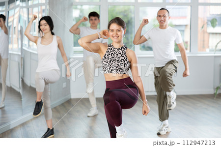 Positive young woman dancing modern dance with other people during group training 112947213