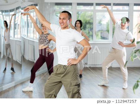 Cheerful Asian fitness instructor leading Zumba class Cheerful Asian fitness instructor leading Zumba class 112947257