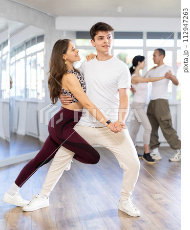 Smiling young woman in sports clothes learn to dance couples latin dance, energetic and fast tango in dance salon 112947263