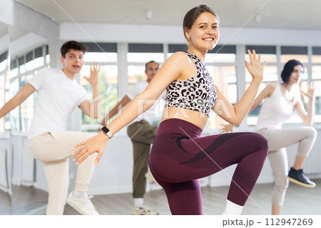 Group of people, girls and guys in sportive casual style clothes dancing in choreography class 112947269