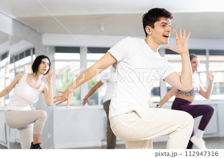 Guy with team of young like-minded people learn to dance modern dances Guy with team of young like-minded people learn to dance modern dances 112947316