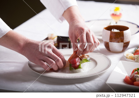 フレンチ料理人　盛り付けする手のアップ　料理を作る男性 112947321