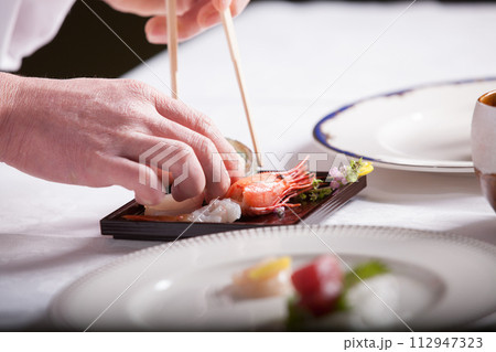フレンチ料理人　盛り付けする手のアップ　料理を作る男性 112947323