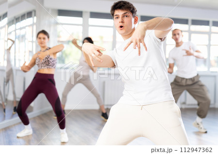 Group of people, girls and guys in sportive casual style clothes dancing in choreography class 112947362