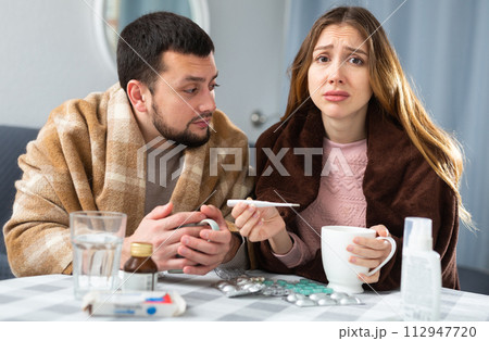 Woman and man wrapped in plaids having symptoms of cold at home 112947720