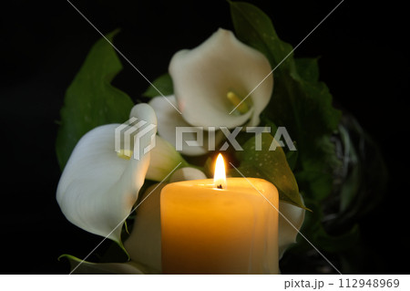 Burning wax candle in close up and white calla lily Burning wax candle in close up and white calla lily 112948969