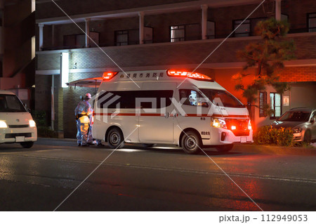 夜間の街中で救急搬送する救急車　イメージ　 112949053