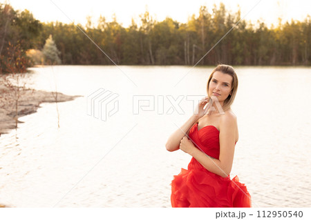 Lakeside Elegance: Serene Woman in a Striking Red Gown Lakeside Elegance: Serene Woman in a Striking Red Gown 112950540