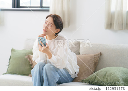 スマホを持ってソファに座っている女性 112951378