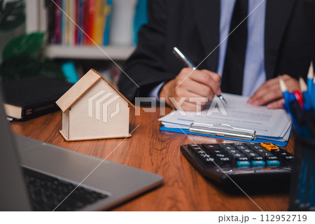 real estate agent with house. Business person holding pen sign a contract approved on mortgage loan contract agreement document house plan on the table. 112952719