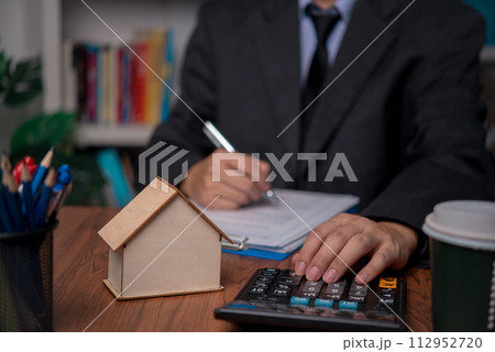 real estate agent with house. Business person holding pen sign a contract approved on mortgage loan contract agreement document house plan on the table. 112952720