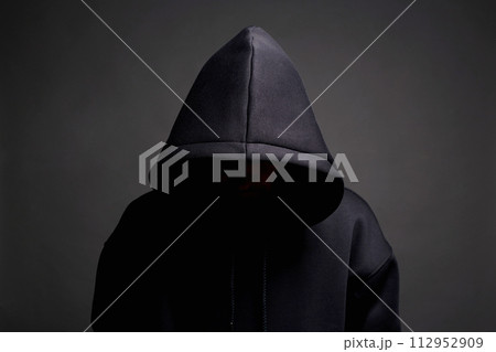 Man in Black Hood posing in dark studio. Boy in a hooded sweatshirt 112952909