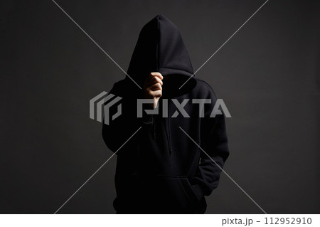 Man in Black Hood posing in dark studio. Boy in a hooded sweatshirt Man in Black Hood posing in dark studio. Boy in a hooded sweatshirt 112952910