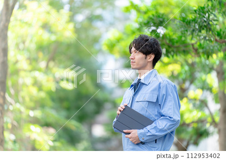 作業着の男性　屋外　新緑　タブレット 112953402