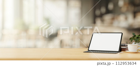 A tablet mockup with a wireless keyboard on a wooden table in a cosy, minimalist coffee shop. 112953634