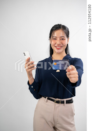 An attractive Asian woman is showing a credit card to the camera, studio background. online payment An attractive Asian woman is showing a credit card to the camera, studio background. online payment 112954180