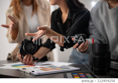 A cropped image of a professional, experienced female photographer working with her team in the studio. A cropped image of a professional, experienced female photographer working with her team in the studio. 112954250