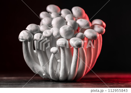 Closeup of a bunch of shimeji mushrooms with red light, on wooden and black background, with selective focus, shimiji mushrooms, superfood, a type of delicious oyster mushroom, healthy food 112955843