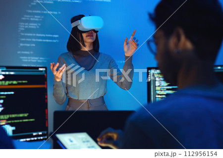 asian and Indian developer devops team testing virtual reality coding and presentation with ai prompt at night in office asian and Indian developer devops team testing virtual reality coding and presentation with ai prompt at night in office 112956154