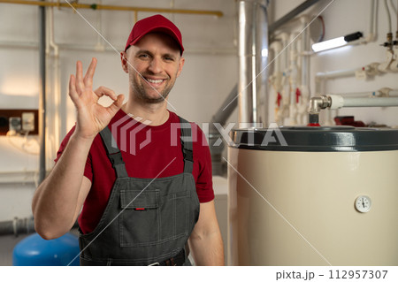 Professional Plumber Inspects Water Heater in Residential Basement Professional Plumber Inspects Water Heater in Residential Basement 112957307