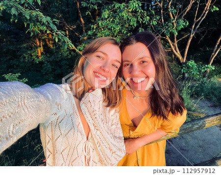 two pretty women take a selfie at sunset two pretty women take a selfie at sunset 112957912