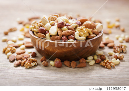 bowl of mixed nuts on wooden table 112958047