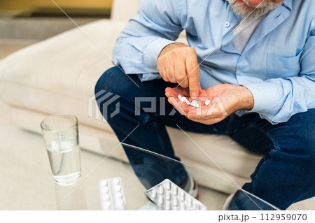 Hands with pills. Senior man hands with medical pill and glass of water. Mature old senior grandfather taking medication cure pills vitamin. Age prescription medicine healthcare therapy concept 112959070