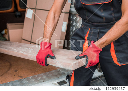 Delivery Worker Unloading Packages from Cargo Vehicle Efficiently Delivery Worker Unloading Packages from Cargo Vehicle Efficiently 112959487