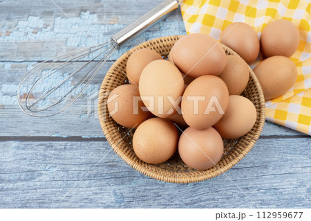 Raw chicken eggs in wooden basket. 112959677