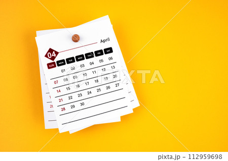 April 2024 calendar page with wooden push pin on yellow background. April 2024 calendar page with wooden push pin on yellow background. 112959698