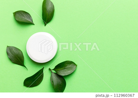 Organic cosmetic product with green leaves on color background. Copy space, flat lay 112960367
